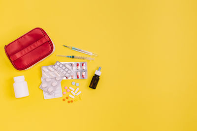 Blisters with pills, syringe, thermometer, nasal drops, bottle with pillules. red first aid kit. 