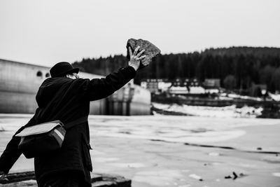 Man holding stone at beach against clear sky