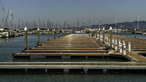 Boats moored at harbor against clear sky