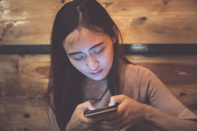 Close-up of young woman using mobile phone at restaurant