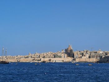 View of buildings by sea against blue sky