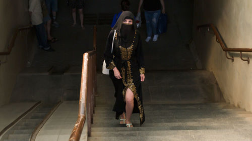 A muslim woman national dress walks through underground passage.