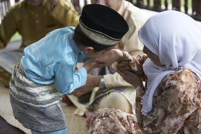 Boy kissing hands of grandmother while sitting in gazebo