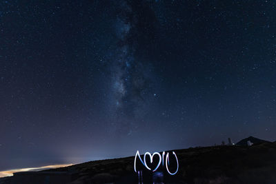 Low angle view of sign against sky at night