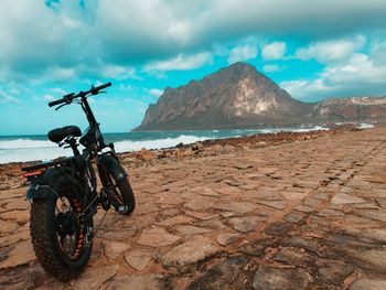 Bicycle by sea against mountains