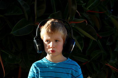 A blond boy listens to music  a young music lover wearing headphones looks thoughtfully to the side.