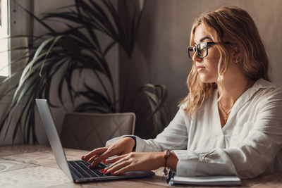 Businesswoman using laptop while sitting on table