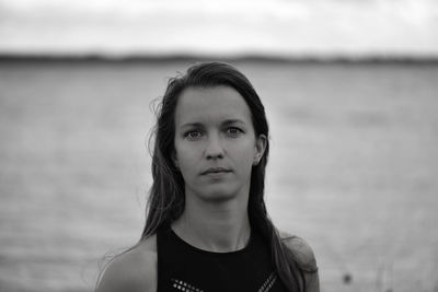 Portrait of young woman standing against sea