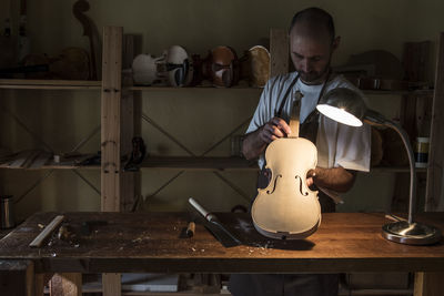 Luthier examining a violin in his workshop