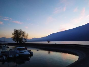 Boats in lake against sky during sunset