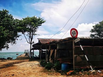 Road sign by building against sky