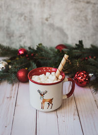 Cup of hot chocolate on white wooden background with christmas decor.