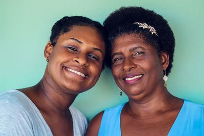 Portrait of mother and daughter standing against wall