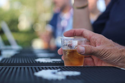 Cropped hand having cocktail in glass on table at party