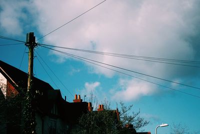 Low angle view of electricity pylon against cloudy sky