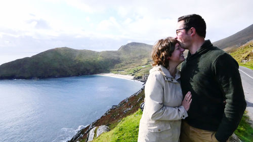 Young couple standing on mountain against sky