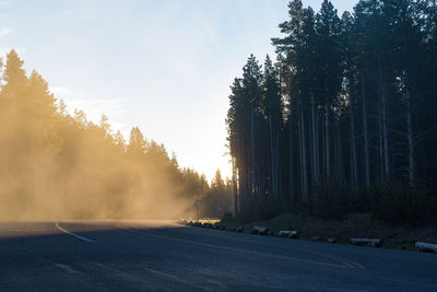 Road amidst trees against sky during sunset