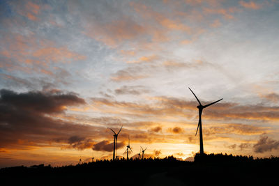 Silhouette of wind turbines in field