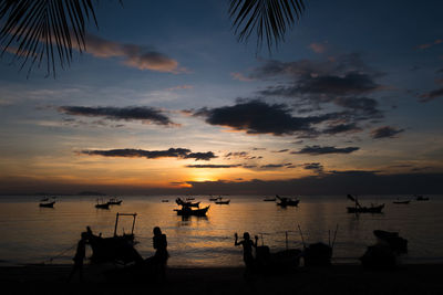 Silhouette boats moored on sea against sky during sunset