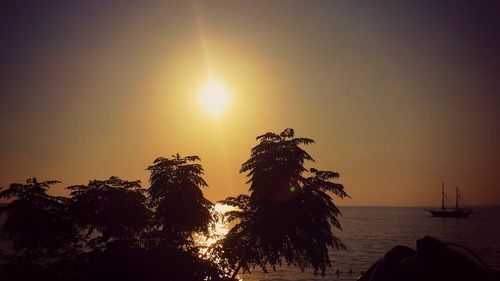 Silhouette trees against sea during sunset