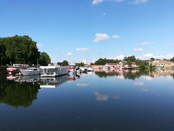 Boats moored in canal by buildings against sky in city