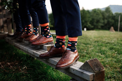 Low section of men standing on wooden railing