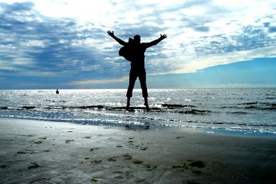 Silhouette of woman jumping on beach