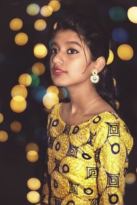 Teenage girl looking away against multi colored illuminated lights