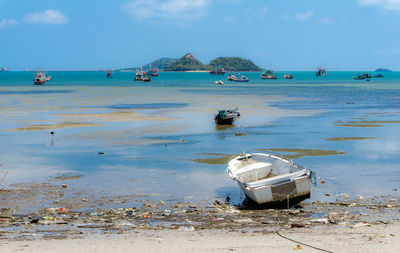 Boat moored on beach against sky