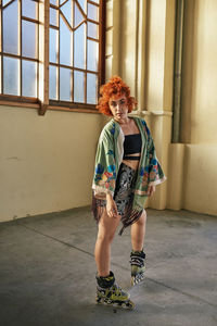 Full length portrait of woman standing against window