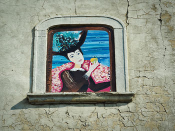 Woman photographing through window on wall of building