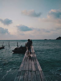 Men standing on pier over sea against sky