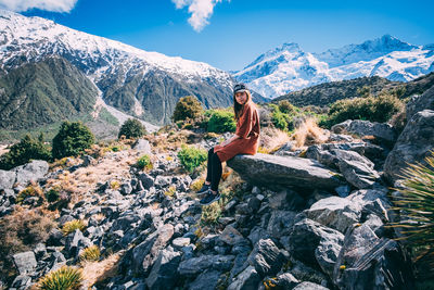 Woman sitting on rock against mountains