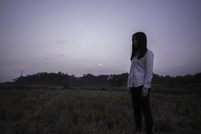 Rear view of woman standing on field against sky