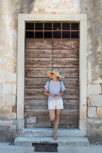 Full length of woman standing against brick wall