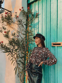 Woman looking away while standing against wall