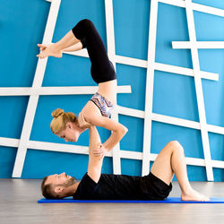 Yoga instructor exercising with woman in yoga class