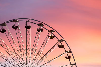 Low angle view of ferris wheel against sky at sunset