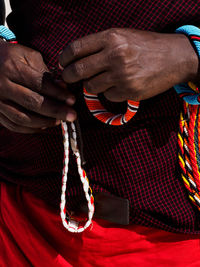 Midsection of man holding bracelets