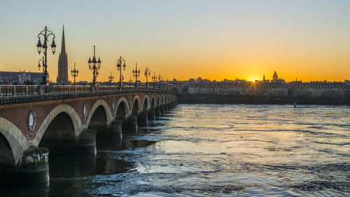 Bridge over river against sky during sunset