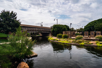 Arch bridge over river by buildings against sky