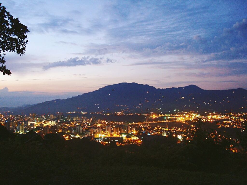 cityscape, illuminated, mountain, building exterior, city, built structure, architecture, sky, mountain range, high angle view, night, residential district, crowded, cloud - sky, residential building, dusk, residential structure, town, landscape, scenics