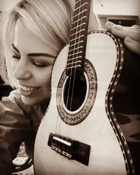 Close-up portrait of a young woman playing guitar