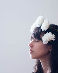 Close-up of woman with pink flowers against white background