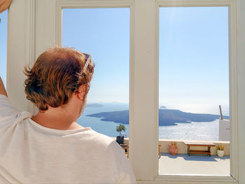 Rear view of woman looking through window