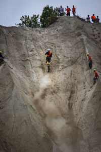 Audience looking at motocross racer moving up on cliff