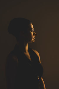 Woman looking away while standing against gray background