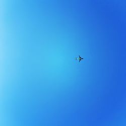 Low angle view of airplane against clear blue sky