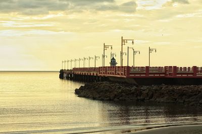 Pier over sea against sky during sunset