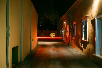 Illuminated alley amidst buildings at night